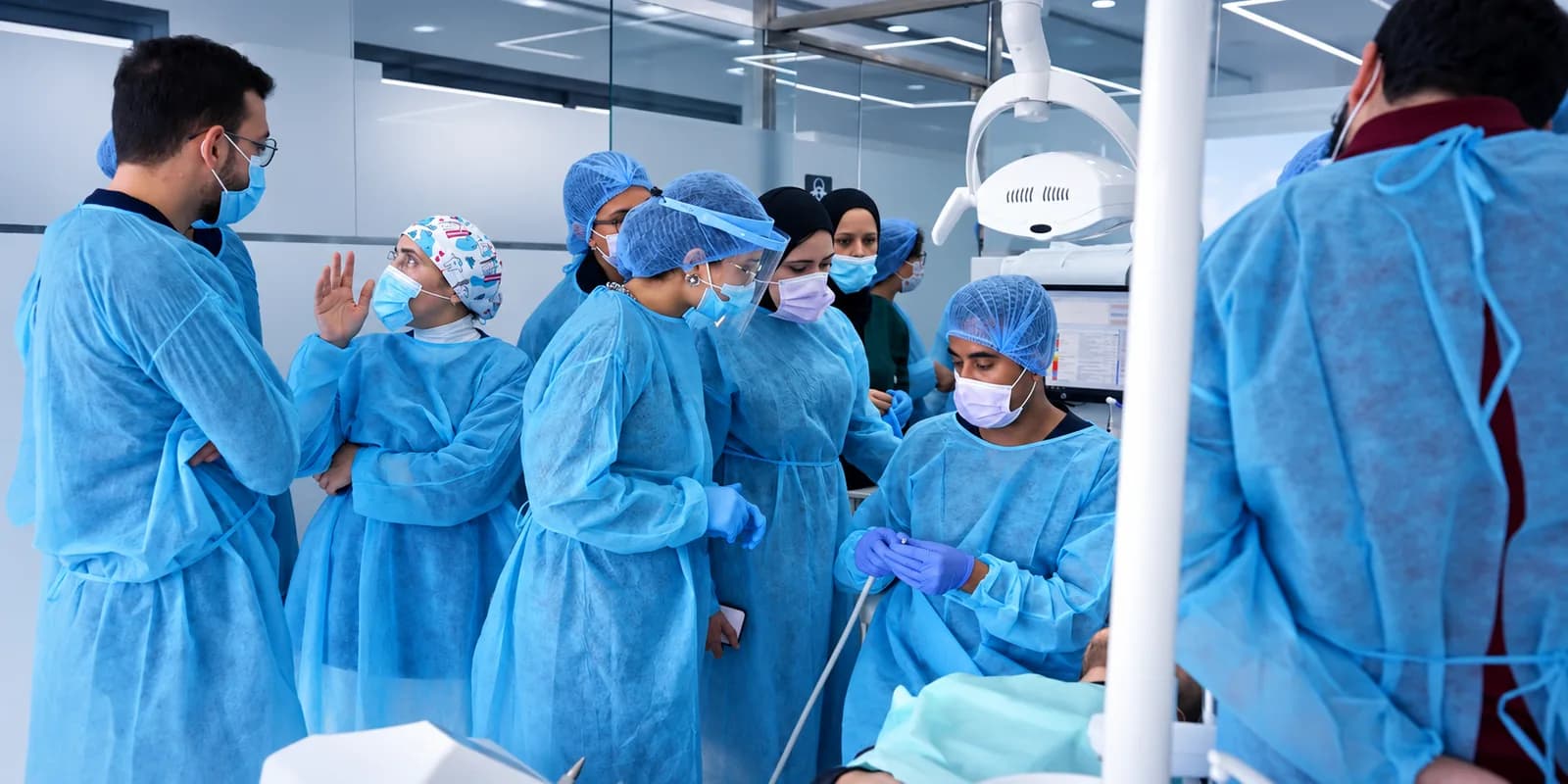 Participants en blouse chirurgicale pendant une vacation clinique de chirurgie orale, Institut Ophelia