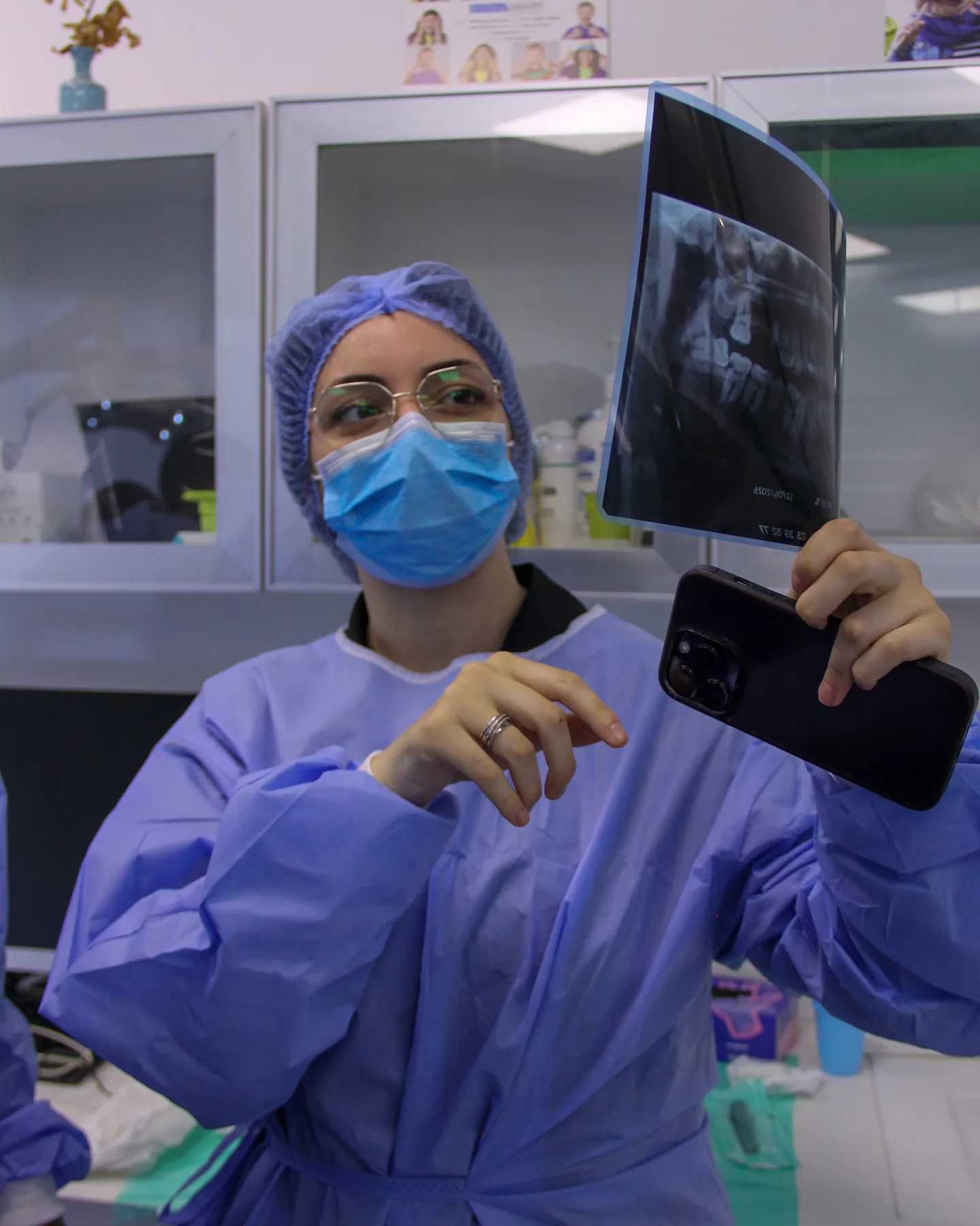 Praticienne en tenue chirurgicale tenant une radiographie panoramique avant l'acte